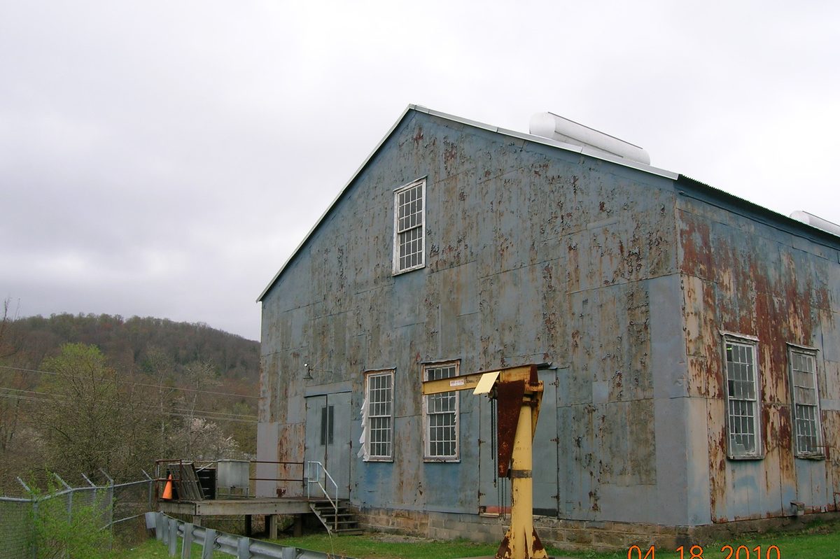 A weathered commercial steel building with rusted, faded panels — the kind of condition we take on