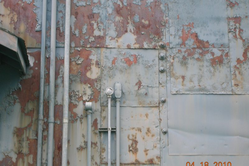 Chalky, faded aluminum siding before refinishing — the white oxidation film that rubs off on your hand